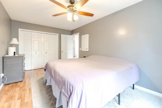 bedroom with baseboards, a ceiling fan, light wood finished floors, and a closet