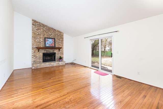 3126 Fairhaven Ct, Ann Arbor, MI 48105 - unfurnished living room with vaulted ceiling, hardwood / wood-style flooring, a brick fireplace, and visible vents