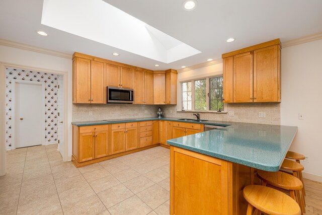 1060 Chestnut St, Ann Arbor, MI 48104 - kitchen with a skylight, a breakfast bar, stainless steel appliances, ornamental molding, and a sink