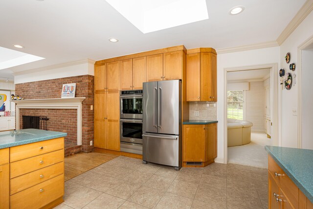 1060 Chestnut St, Ann Arbor, MI 48104 - kitchen featuring stainless steel appliances, dark countertops, a skylight, and a brick fireplace