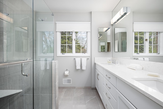 1060 Chestnut St, Ann Arbor, MI 48104 - bathroom featuring a shower stall, double vanity, a sink, baseboards, and visible vents