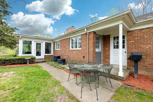 1060 Chestnut St, Ann Arbor, MI 48104 - back of property with a chimney, brick siding, a patio, outdoor dining area, and a lawn