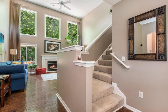 5591 E Grove Dr SE, Grand Rapids, MI 49512 - staircase with a ceiling fan, a warm lit fireplace, hardwood / wood-style floors, and a towering ceiling