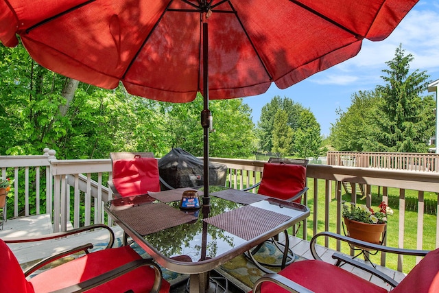 5591 E Grove Dr SE, Grand Rapids, MI 49512 - deck featuring outdoor dining space, a lawn, and view of wooded area