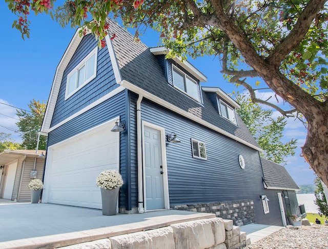 view of home's exterior with a shingled roof, driveway, and an attached garage
