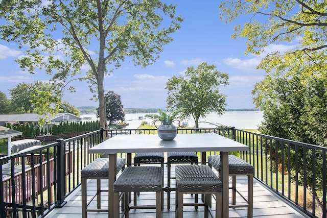deck with outdoor dining area and a water view
