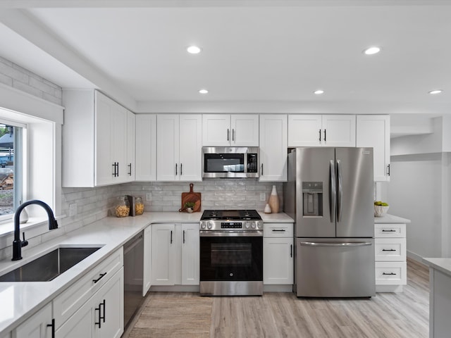 kitchen featuring white cabinets, light wood-style floors, appliances with stainless steel finishes, and a sink