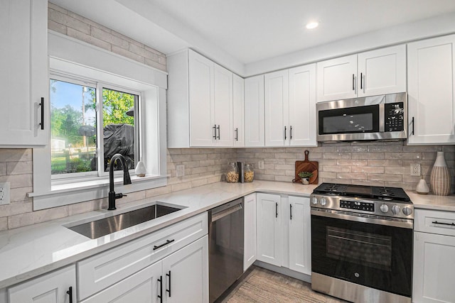 kitchen with a sink, white cabinetry, stainless steel appliances, and tasteful backsplash
