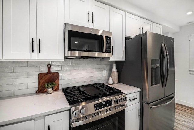 kitchen featuring light stone counters, backsplash, white cabinetry, and stainless steel appliances