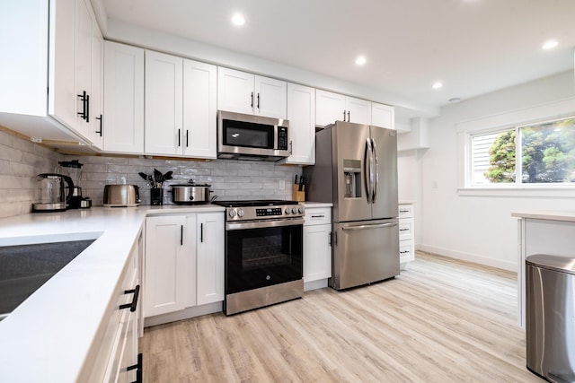 kitchen with backsplash, white cabinets, appliances with stainless steel finishes, and light countertops