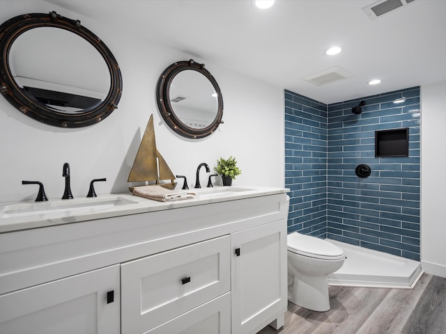 full bathroom featuring a sink, toilet, double vanity, visible vents, and wood finished floors