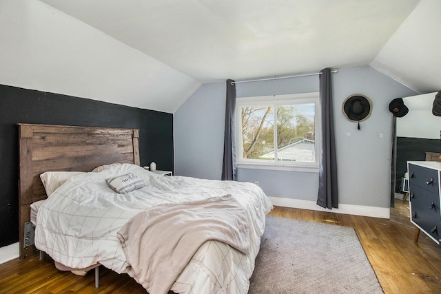 bedroom with vaulted ceiling, baseboards, and wood finished floors