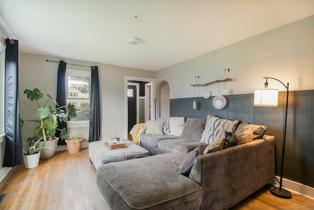 living room with arched walkways, hardwood / wood-style floors, and visible vents