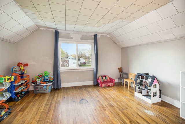 recreation room featuring wood-type flooring, vaulted ceiling, and baseboards
