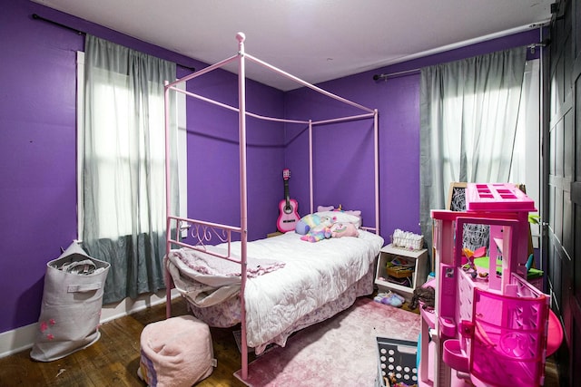 bedroom with multiple windows and wood finished floors