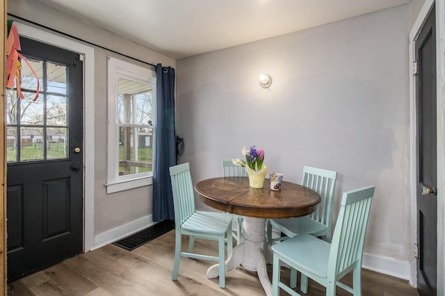 dining area featuring baseboards, wood finished floors, and visible vents