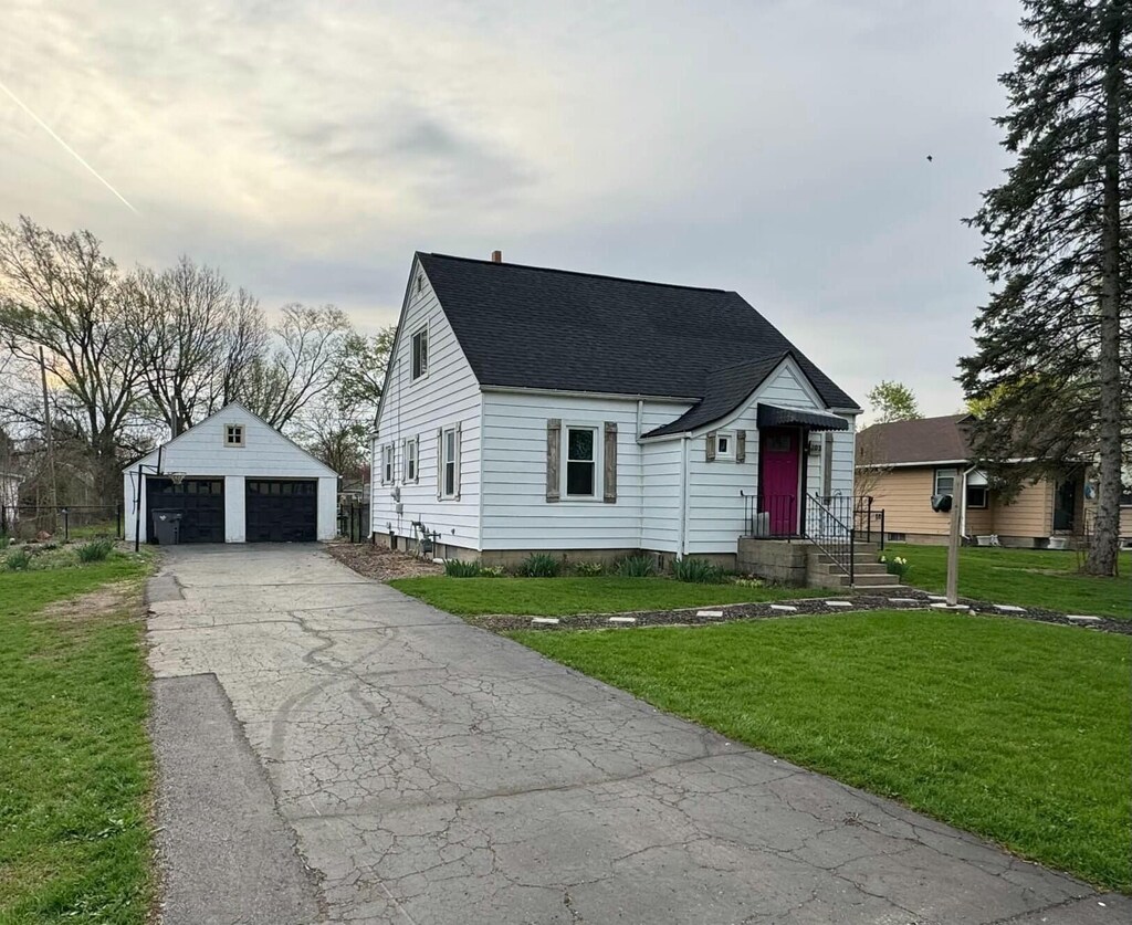 202 N Laird St, White Pigeon, MI 49099 - cape cod house with roof with shingles, an outbuilding, a front yard, and a garage