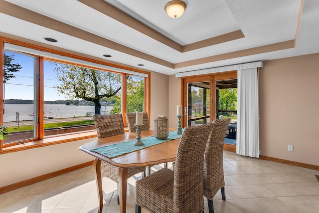 150 Hyde Rd, Clarklake, MI 49234 - dining area with baseboards, a water view, a tray ceiling, and light tile patterned floors