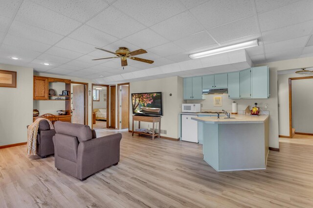 living area with light wood-style floors, baseboards, a ceiling fan, and a paneled ceiling