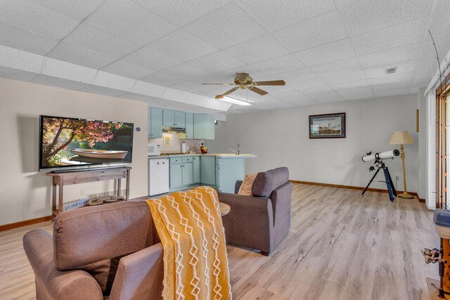 living room with baseboards, a ceiling fan, a paneled ceiling, and light wood-style flooring
