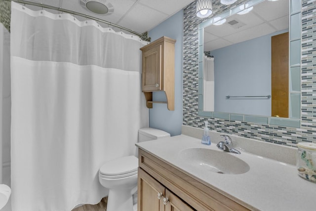 bathroom with toilet, visible vents, a drop ceiling, and tasteful backsplash