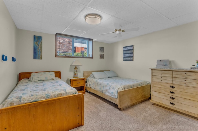 carpeted bedroom featuring ceiling fan and a paneled ceiling