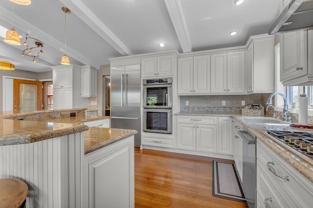 kitchen with tasteful backsplash, white cabinetry, a sink, stainless steel appliances, and light wood-style flooring