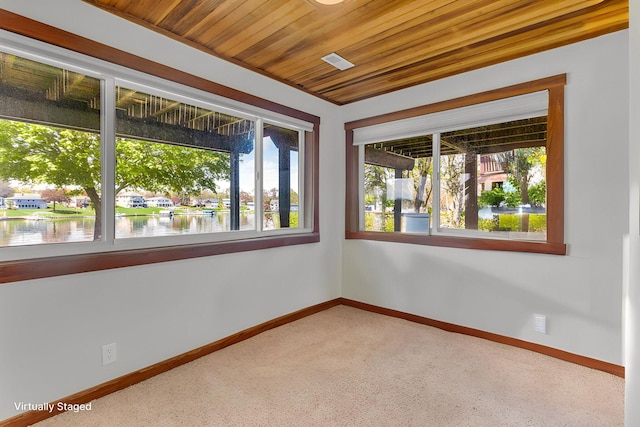 carpeted spare room with a water view, baseboards, and wood ceiling