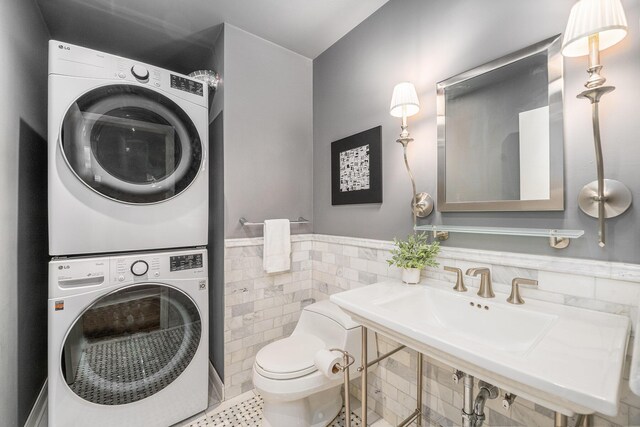 4040 Greenleaf Cir Unit 301, Kalamazoo, MI 49008 - bathroom with tile patterned flooring, stacked washer and dryer, toilet, tile walls, and a wainscoted wall