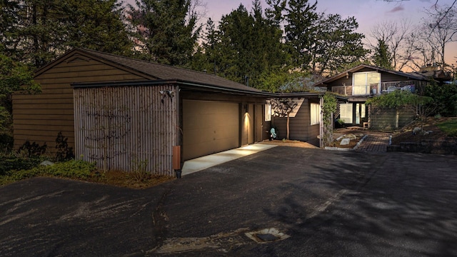 garage at dusk featuring aphalt driveway