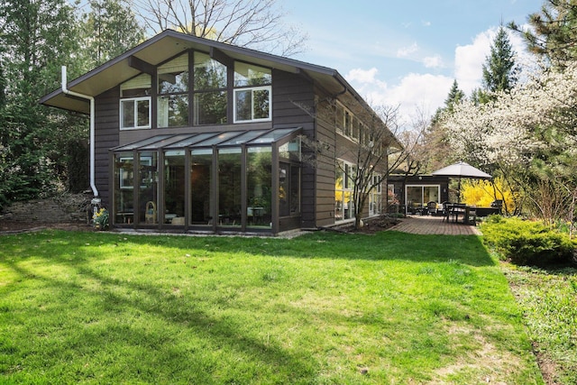 rear view of house featuring a sunroom, a lawn, and a deck