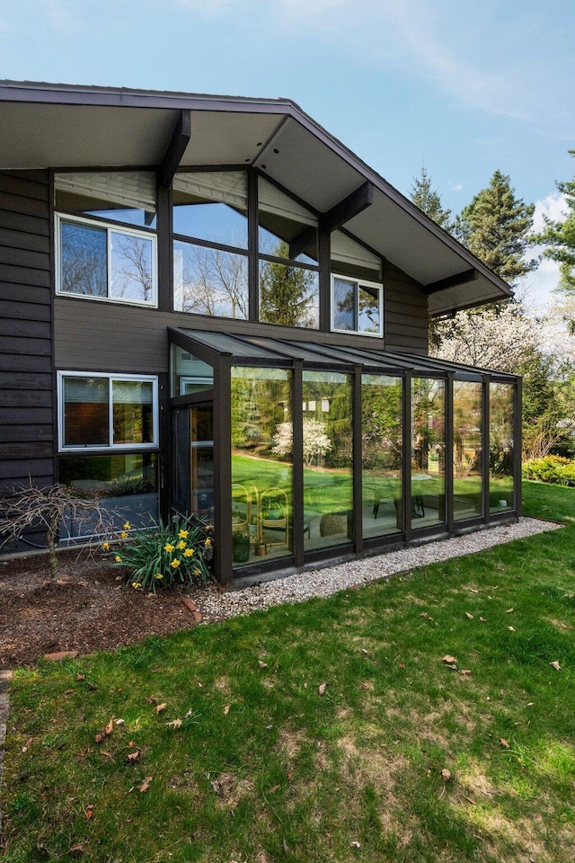 back of property featuring a yard and a sunroom