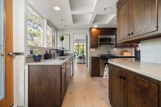 kitchen with light countertops, stainless steel appliances, decorative backsplash, and a sink