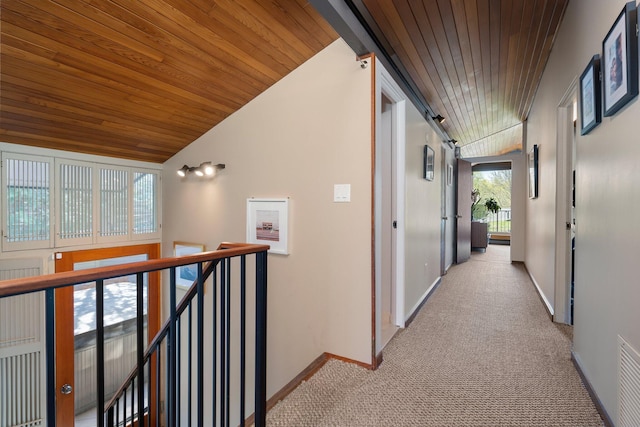 hall with baseboards, lofted ceiling, light carpet, and wooden ceiling
