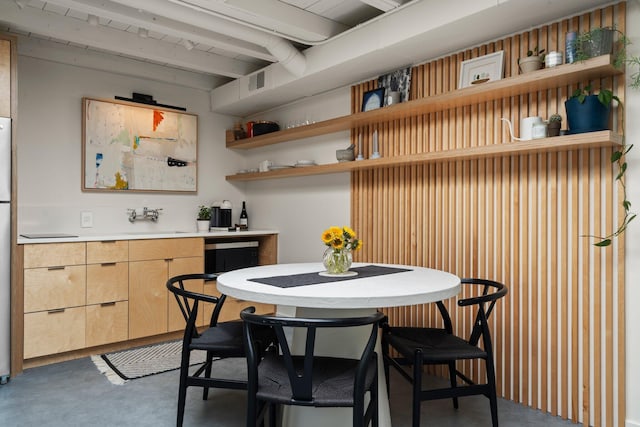 interior space with open shelves, concrete flooring, and light brown cabinets