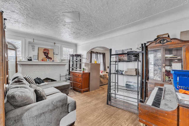 15885 Indiana St, Detroit, MI 48238 - living room featuring arched walkways, a fireplace, a textured ceiling, and wood finished floors