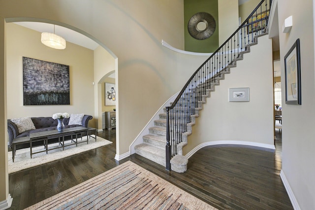 51583 Turnburry Dr, South Lyon, MI 48178 - entrance foyer featuring arched walkways, wood finished floors, stairway, baseboards, and a high ceiling