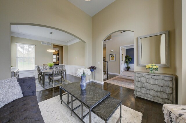 51583 Turnburry Dr, South Lyon, MI 48178 - living area with crown molding, dark wood-style flooring, arched walkways, a towering ceiling, and visible vents