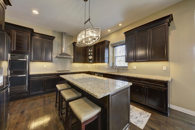 51583 Turnburry Dr, South Lyon, MI 48178 - kitchen with wall chimney range hood, appliances with stainless steel finishes, tasteful backsplash, a center island, and a sink