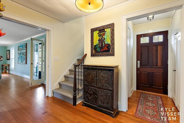 entrance foyer with stairway, baseboards, ornamental molding, and hardwood / wood-style flooring