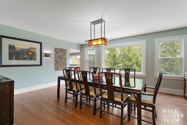 dining area with baseboards, visible vents, and wood finished floors