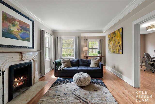 living area featuring crown molding, baseboards, and light wood-style flooring