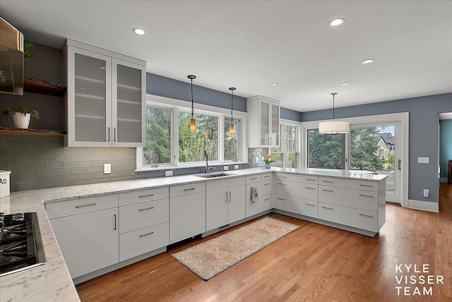 kitchen with white cabinets, open shelves, a sink, gas stovetop, and backsplash