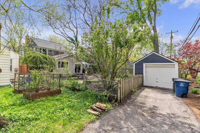 1115 Henry St, Ann Arbor, MI 48104 - view of yard with a vegetable garden, asphalt driveway, an outbuilding, and a detached garage