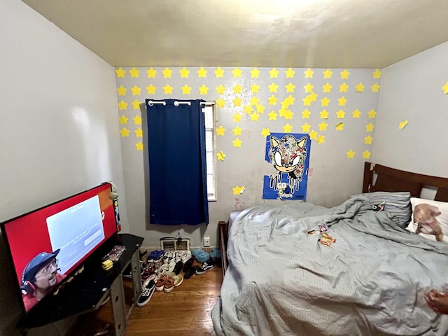 bedroom featuring wood finished floors and an accent wall