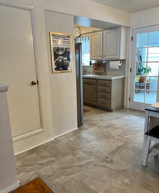 kitchen with baseboards, light countertops, a sink, and freestanding refrigerator