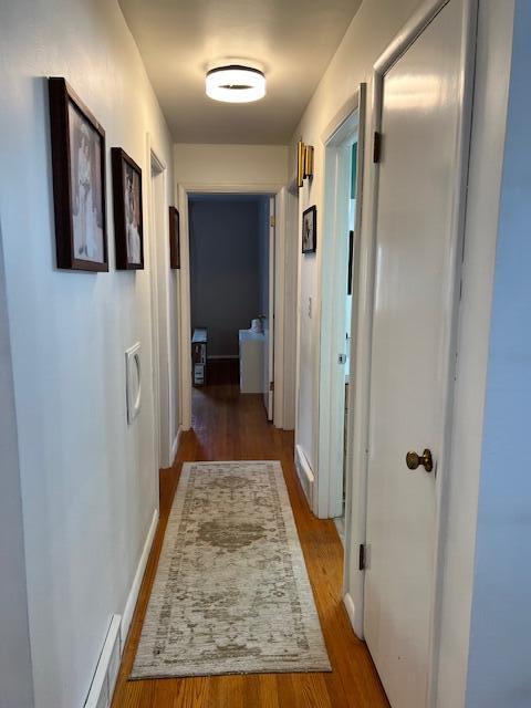 corridor with baseboards, wood finished floors, and visible vents