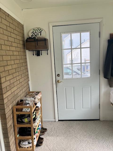 doorway featuring carpet flooring and brick wall