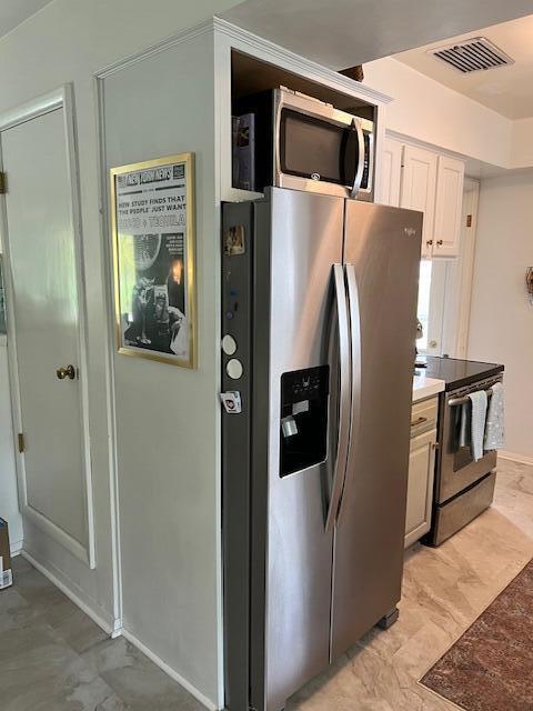 kitchen featuring visible vents, baseboards, white cabinetry, and stainless steel appliances