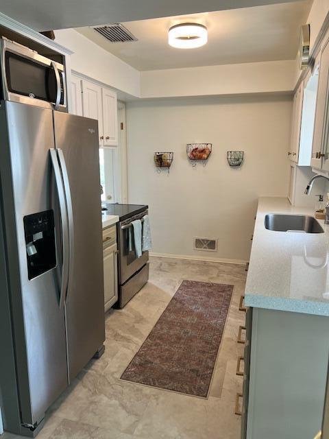 kitchen featuring light countertops, stainless steel appliances, visible vents, and a sink